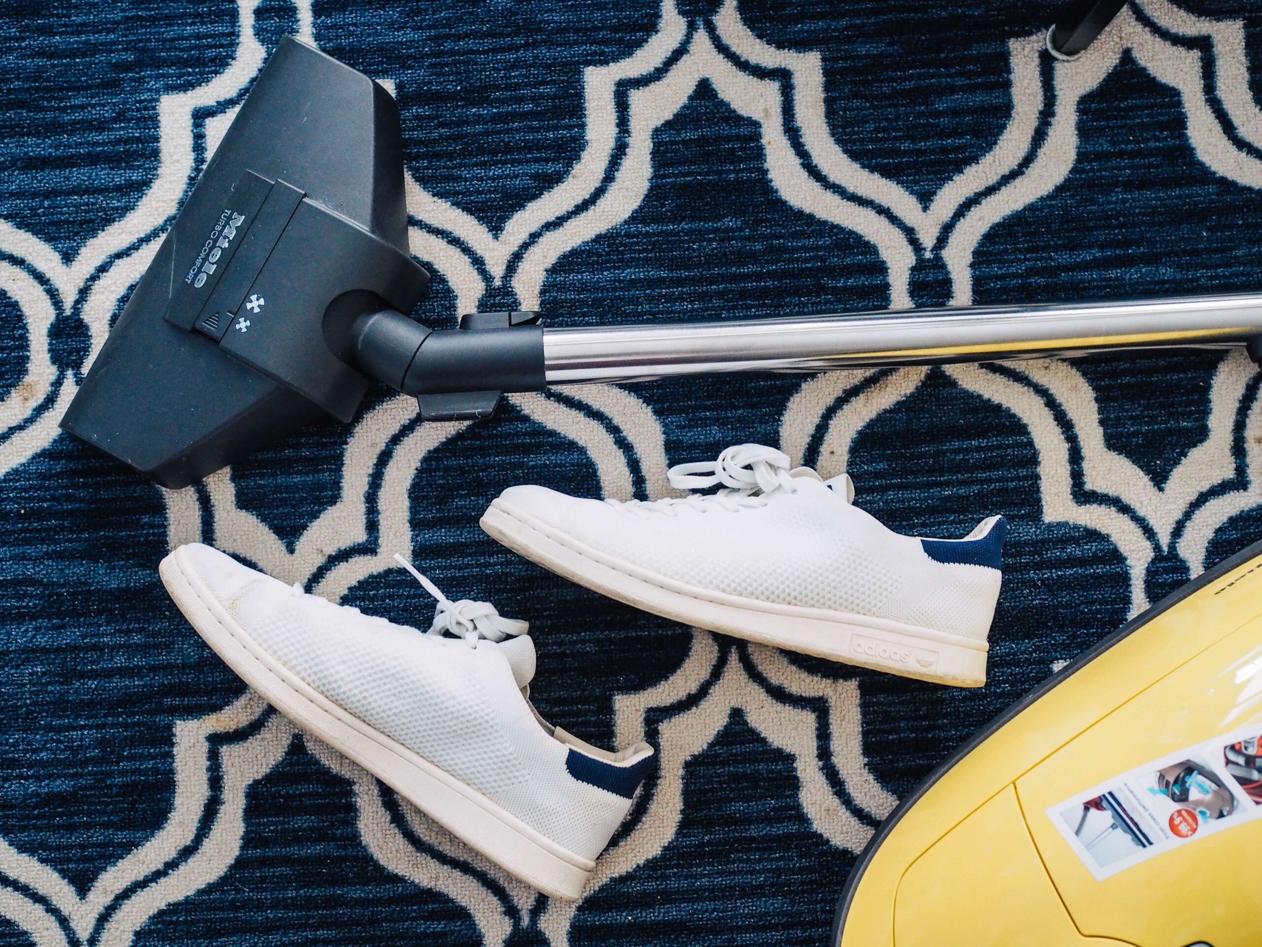 vacuum cleaner and shoes resting on patterned carpet