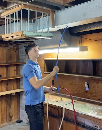 male technician in blue shirt cleaning an air duct