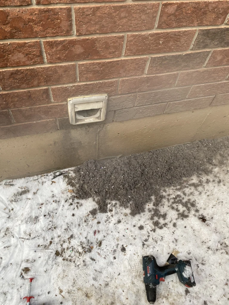 dryer vent exhaust on side of house with lots of removed lint